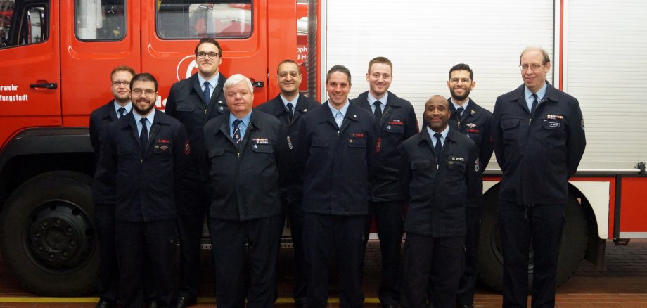 Gruppenbild: Feuerwehrleute vor Einsatzwagen