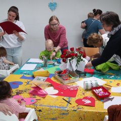 Viele Mütter basteln mit ihren kleinen Kindern Geschenke an einem großen Tisch