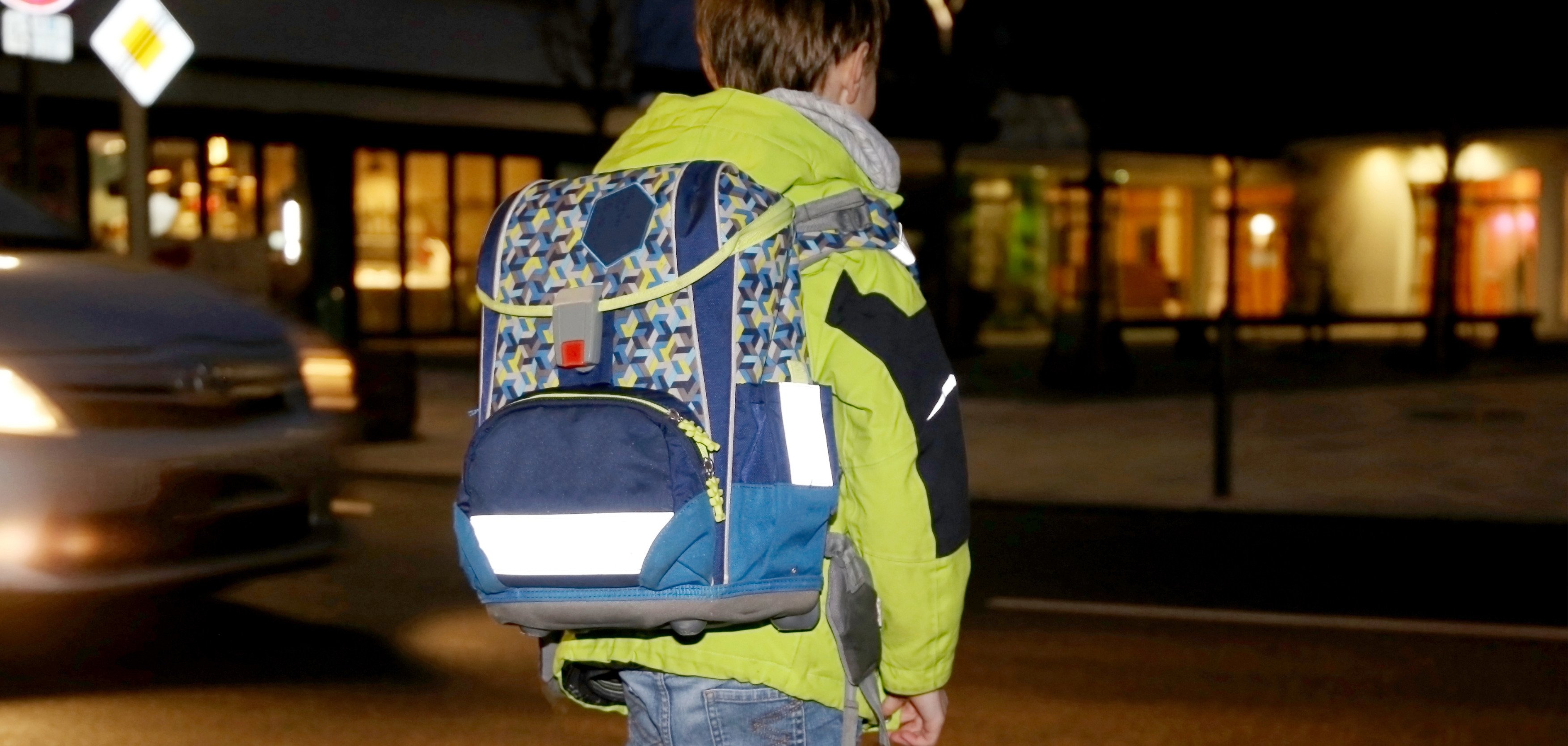 Kind im Dunkeln mit reflektierendem Schulranzen