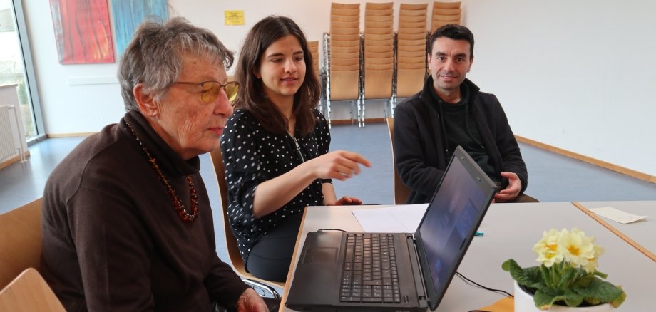 Junge Menschen erklären einer älteren Dame die Funktionen der digitalen Welt  