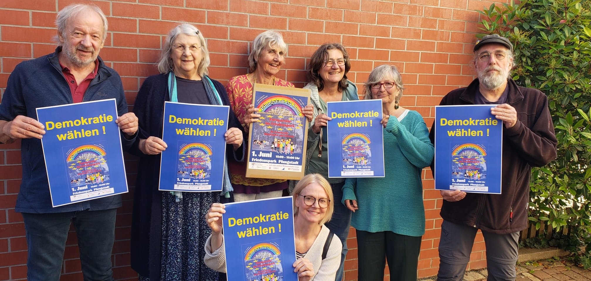 Ältere Menschen halten ein Veranstaltungsplakat in der Hand