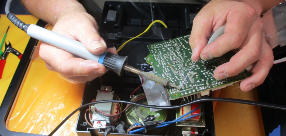 Repaircafé Reparatur mit Lötkolben einer elektronischen Platine