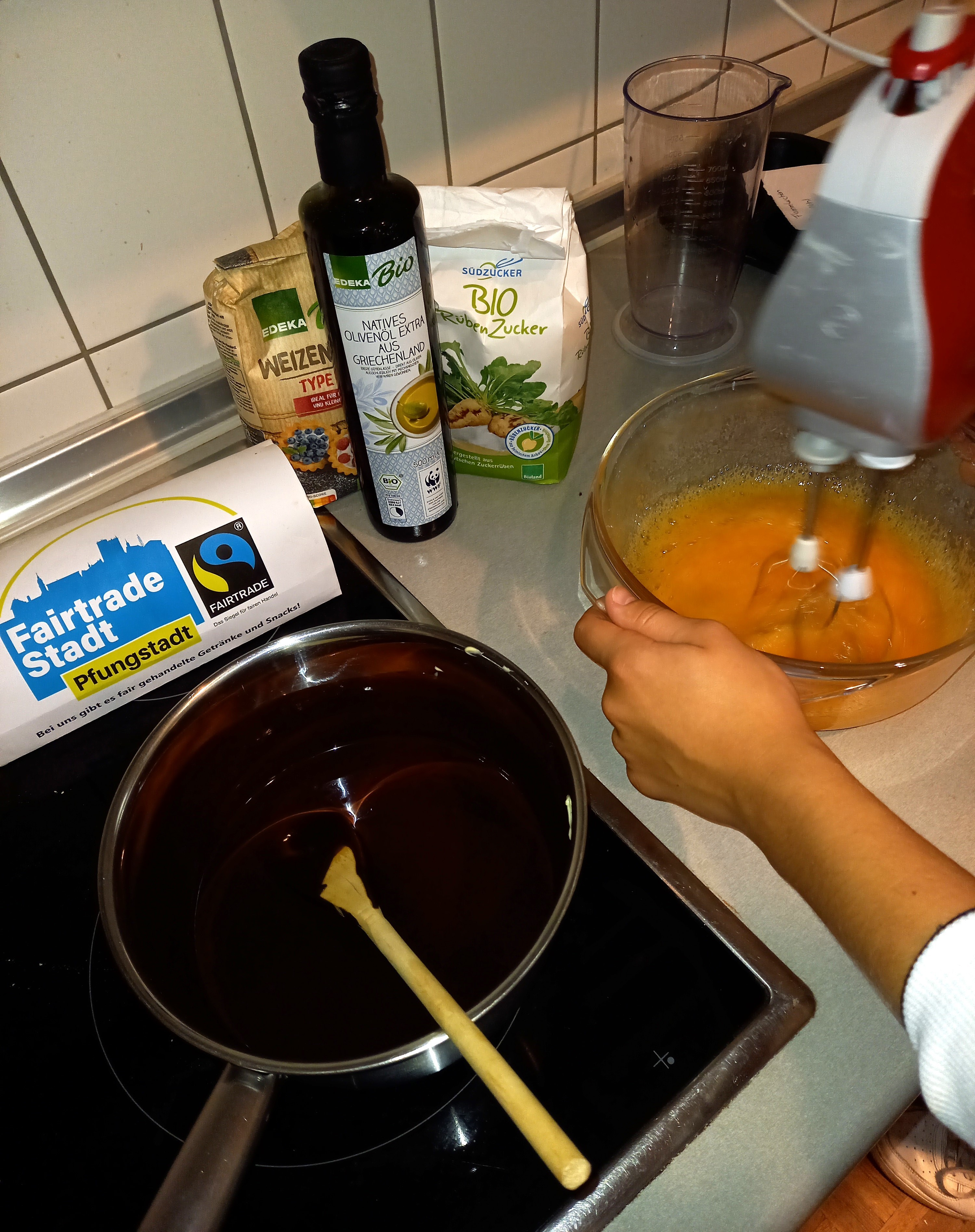 Eine Pfanne auf dem Herd, eine gelbe Masse in einer Schüssel wird mit einem Mixgerät gerührt