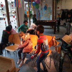Kinder sitzen auf Stühlen bzw. laufen um die Stühle