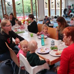 Eltern und Kinder sitzen an einem Tisch und essen Kuchen