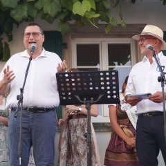 Zwei Männer auf einer Bühne halten eine Rede