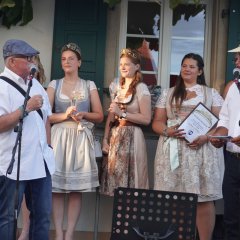 Weinprinzessinnen mit zwei Herren auf der Bühne, die eine Rede halten