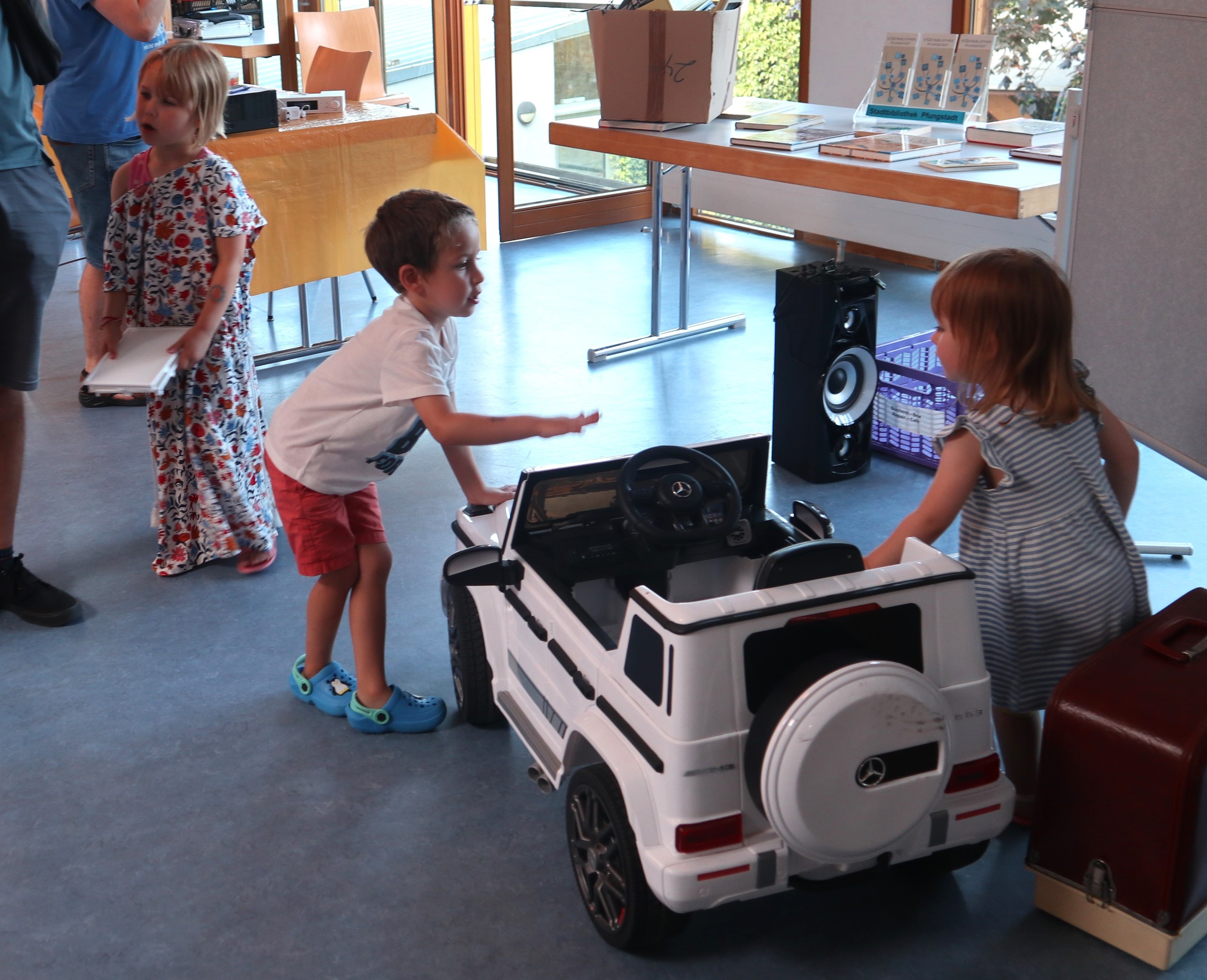 Ein Mädchen und ein Junge spielen mit elektrischen Auto
