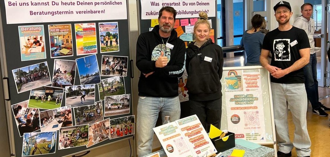 Zwei Männer und eine Frau stehen an einem Messestand