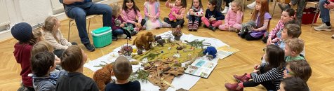 Frau erzählt Kindern, die im Kreis sitzen, eine Geschichte