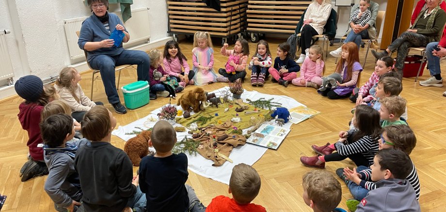 Frau erzählt Kindern, die im Kreis sitzen, eine Geschichte