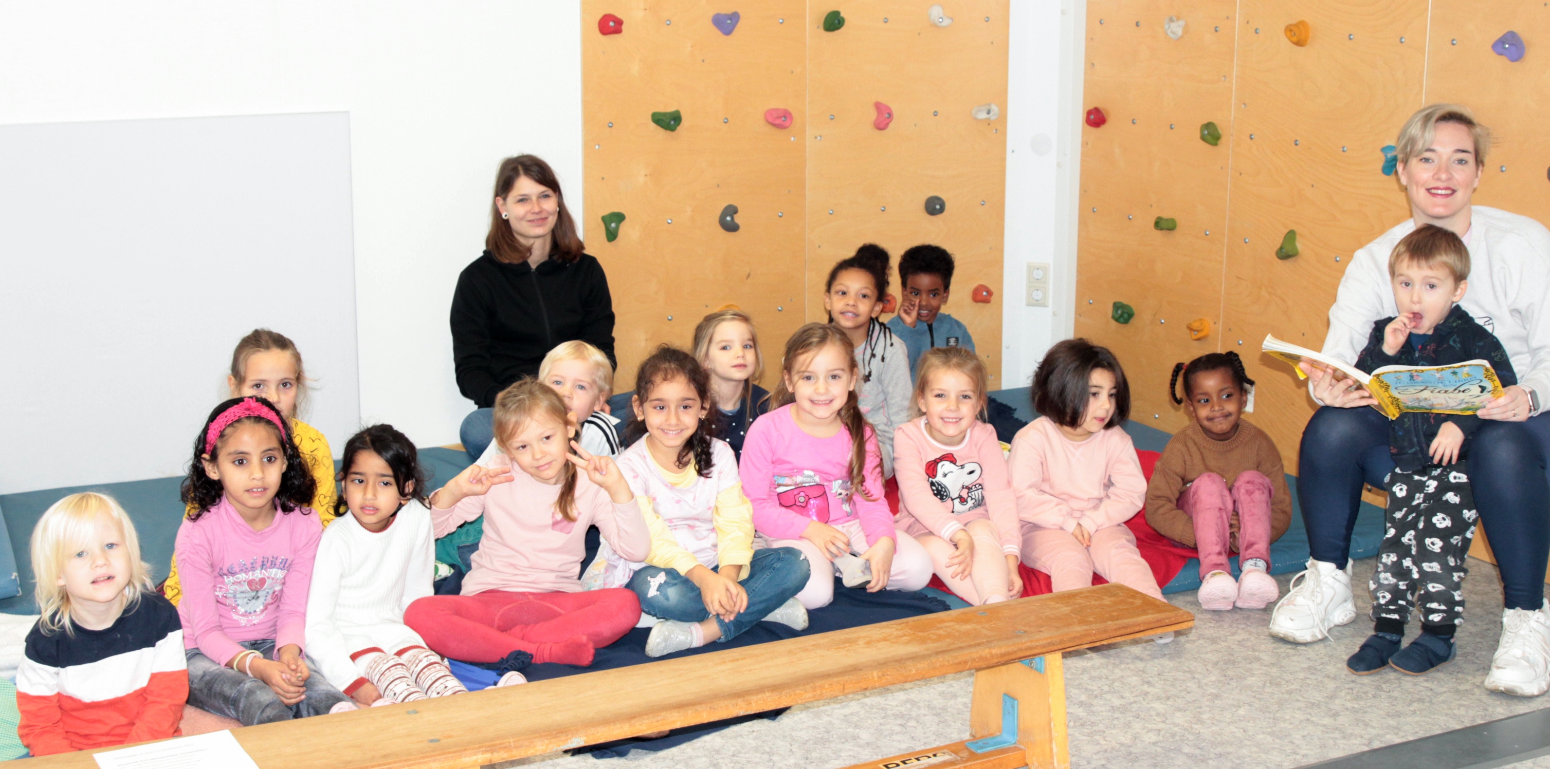 Zwei Frauen und viele Kinder sitzen auf dem Boden 