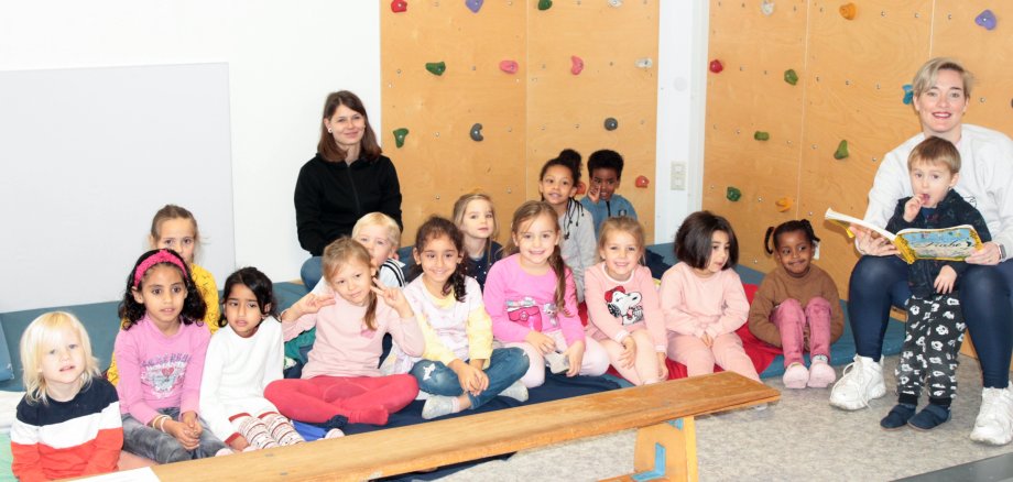 Zwei Frauen und viele Kinder sitzen auf dem Boden 