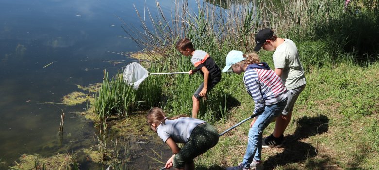 Kinder an einem See mit Fischnetzen in der Hand