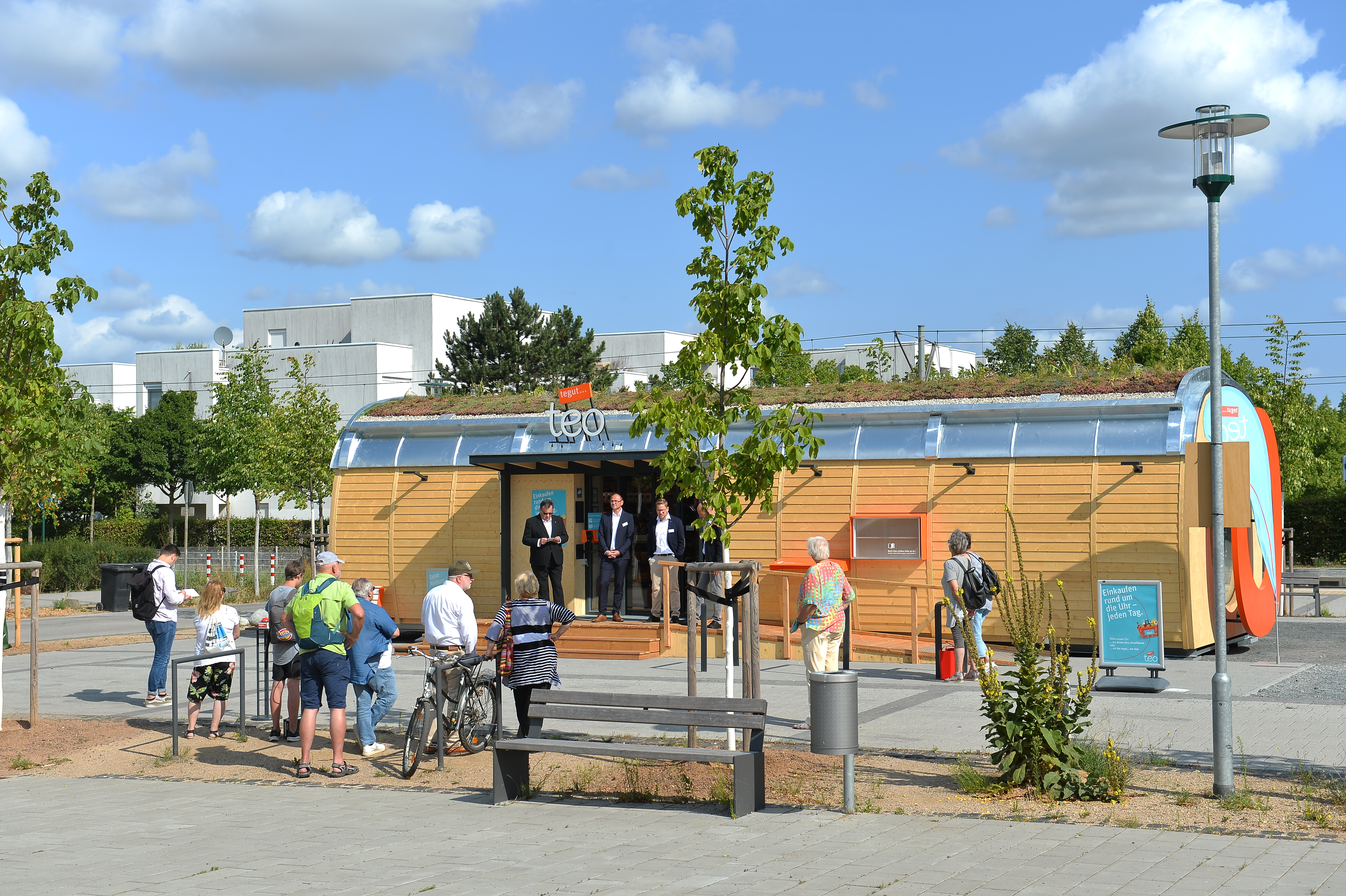 Mini-Supermarkt auf Parkplatz und einigen Menschen im Vordergrund