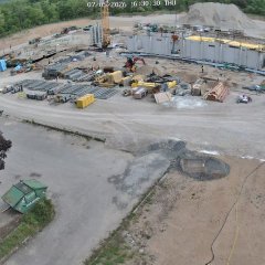 Großbaustelle mit vielen Gerätschaften im Vordergrund und diversen Rohren