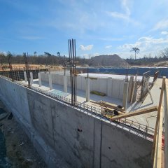 Großbaustelle: Betonplatte mit Wänden und Sandhügel im Hintergrund