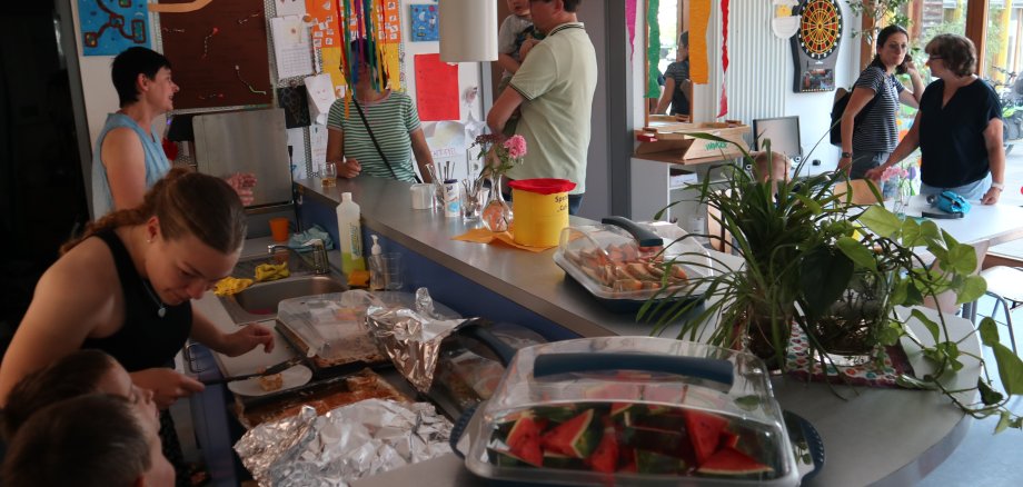 Junge Frau verteilt Kuchen an Kinder und Erwachsene