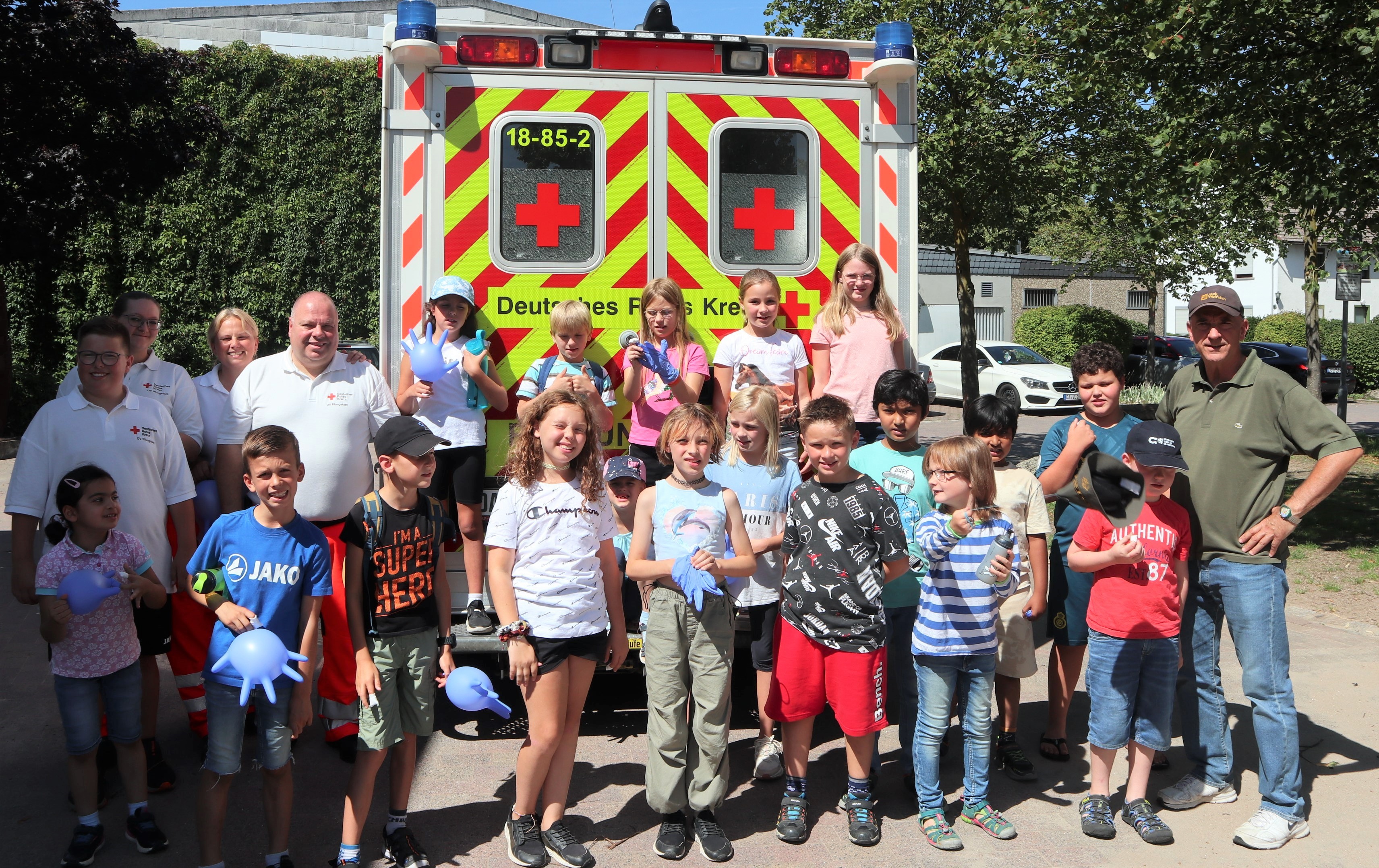 Gruppenfoto mit Kindern und DRK vor einem Rettungswagen