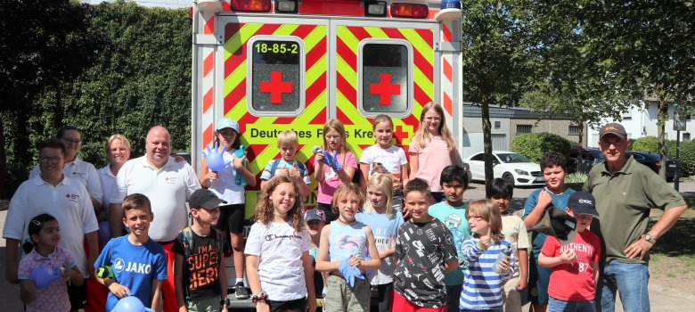 Gruppenfoto mit Kindern und DRK vor einem Rettungswagen