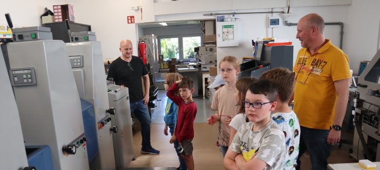 Kinder sehen sich große Druckmaschinen an