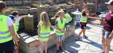 Kinder in gelben Warnwesten begutachten einen Brunnen auf dem Gelände des Natursteinzentrums Rhein-Main.