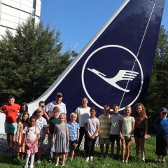 Kinder-Gruppenfoto vor dem Seitenruder eines Lufthansa-Flugzeuges