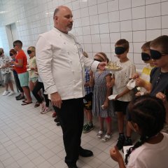 Koch macht mit Kindern eine Kostprobe mit verbundenen Augen