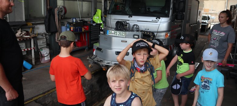 Kinder in der Werkstatt vor einem silbernen LKW