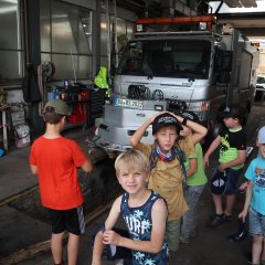Kinder in der Werkstatt vor einem silbernen LKW