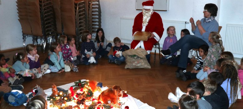 Viele Kinder und ein Nikolaus sitzen in einem großen Kreis  