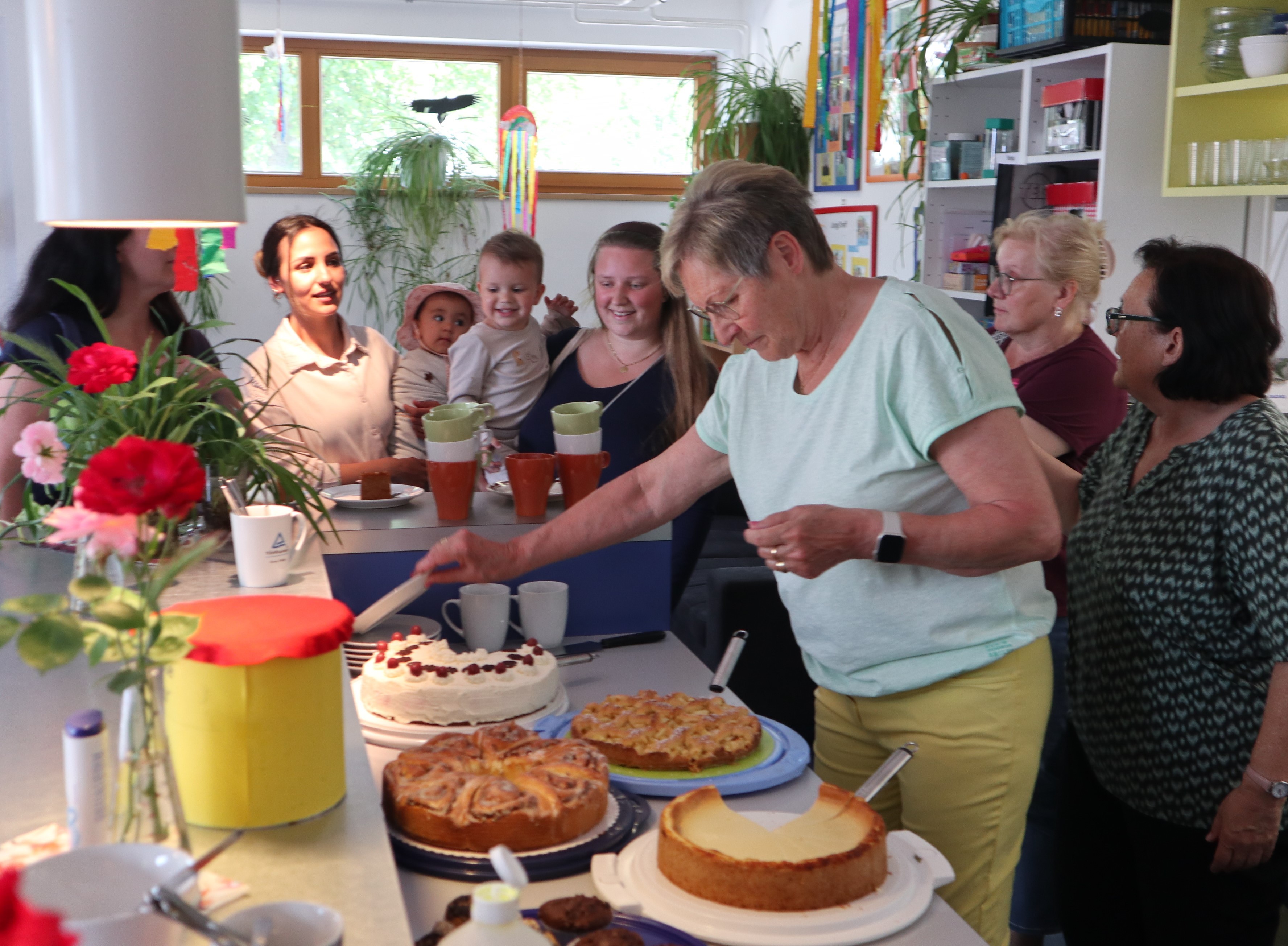 Frau verteilt Kuchen an Mütter mit Kindern