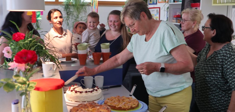 Frau verteilt Kuchen an Mütter mit Kindern