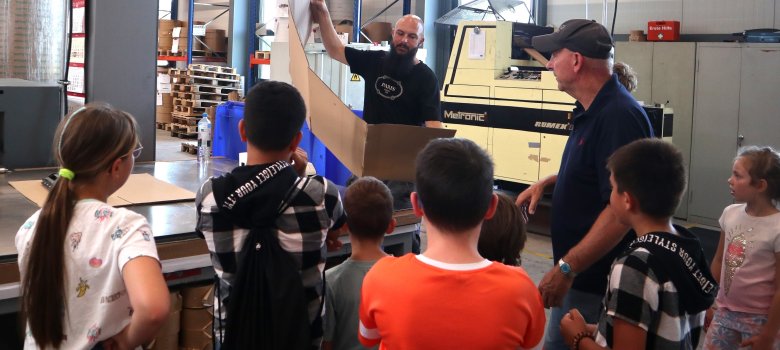 Kinder besichtigen eine Firma für Lastenklebebänder für Kartons
