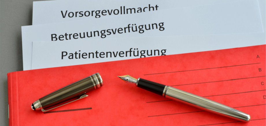 Füller auf roter Mappe mit drei Schriftstücken