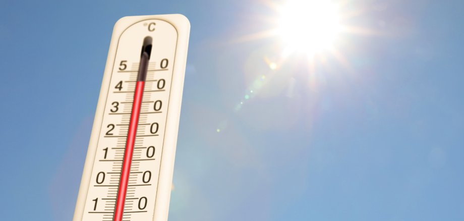 Angepasste Schließzeiten des Wertstoffhofs bei hohen Temperaturen Blauer Himmel und Sonne. Im Vordergrund ein Termometer