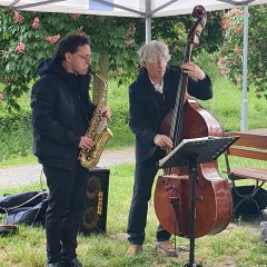 Zahlreiche Besucherinnen und Besucher genießen stimmungsvollen Abend mit Wein, Kulinarik und Musik im Park der Villa Büchner Zwei Musiker spielen mit Saxophon und Kontrabass
