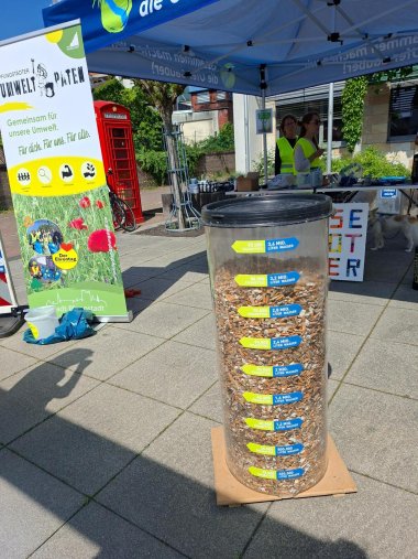 Großer Behälter mit gesammelten Zigarettenkippen, dahinter ein Rollup der Umweltpaten Pfungstadt